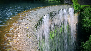 Waterfall over an old dam surrounded by forest