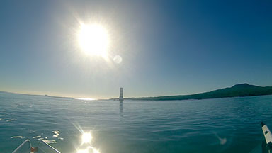 Motor boat fisheye view passing lighthouse