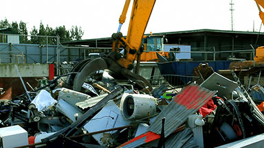 Excavator loads scrap metal junk into bin
